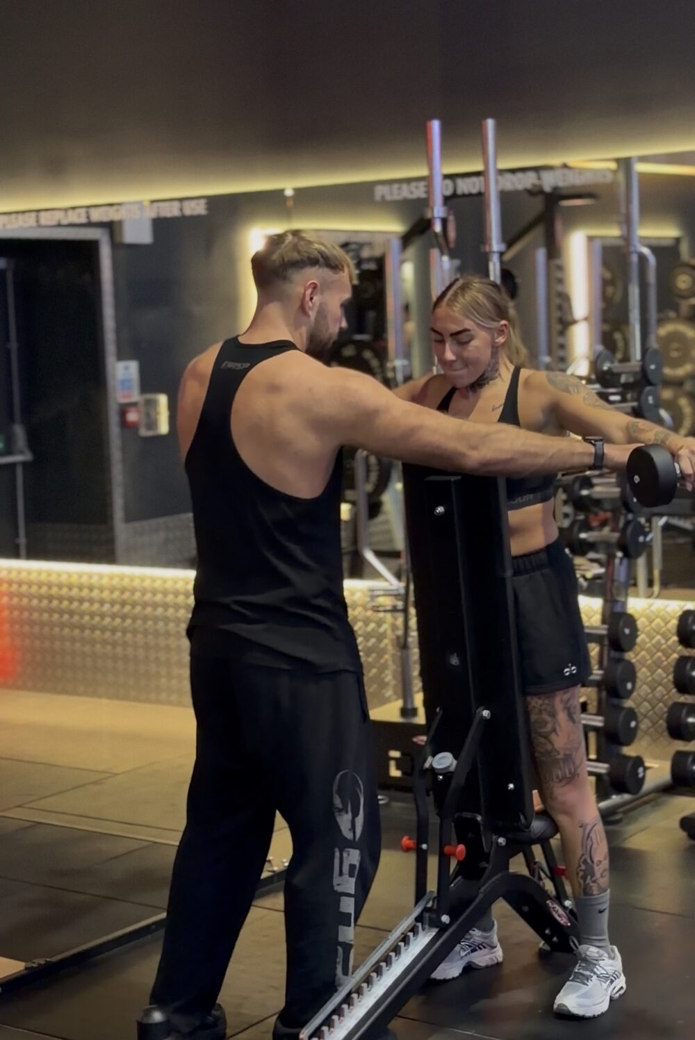 Sculpt Society coach guiding a client through a dumbbell raise